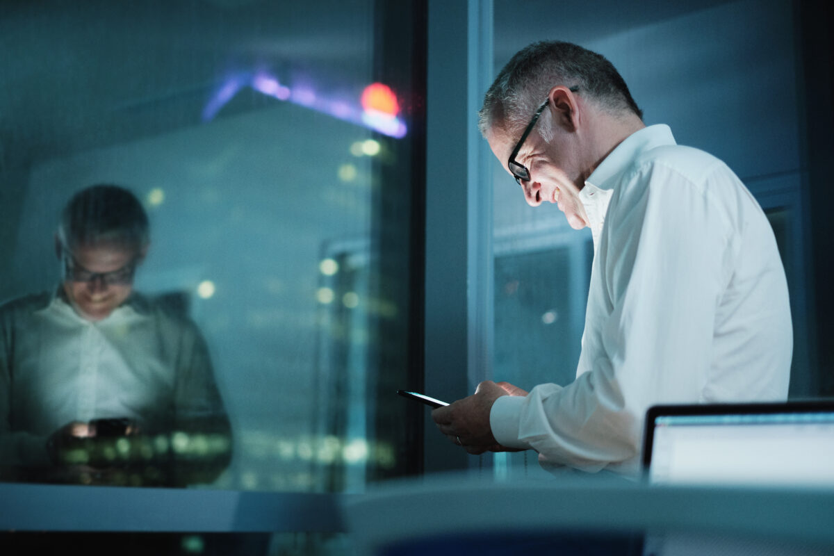Happy Manager Using Smartphone In Dark Office At Night