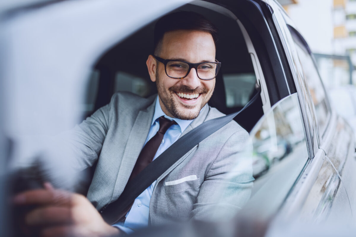 Cheerful Caucasian Businessman Driving Himself To Work. Hands Ar